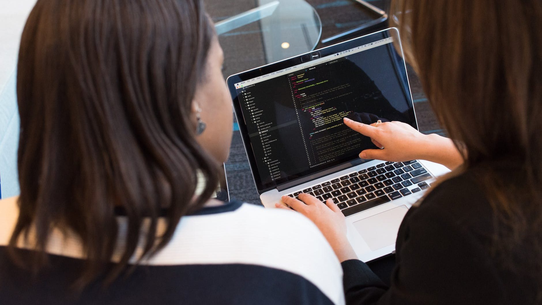 two women looking at the code at laptop
